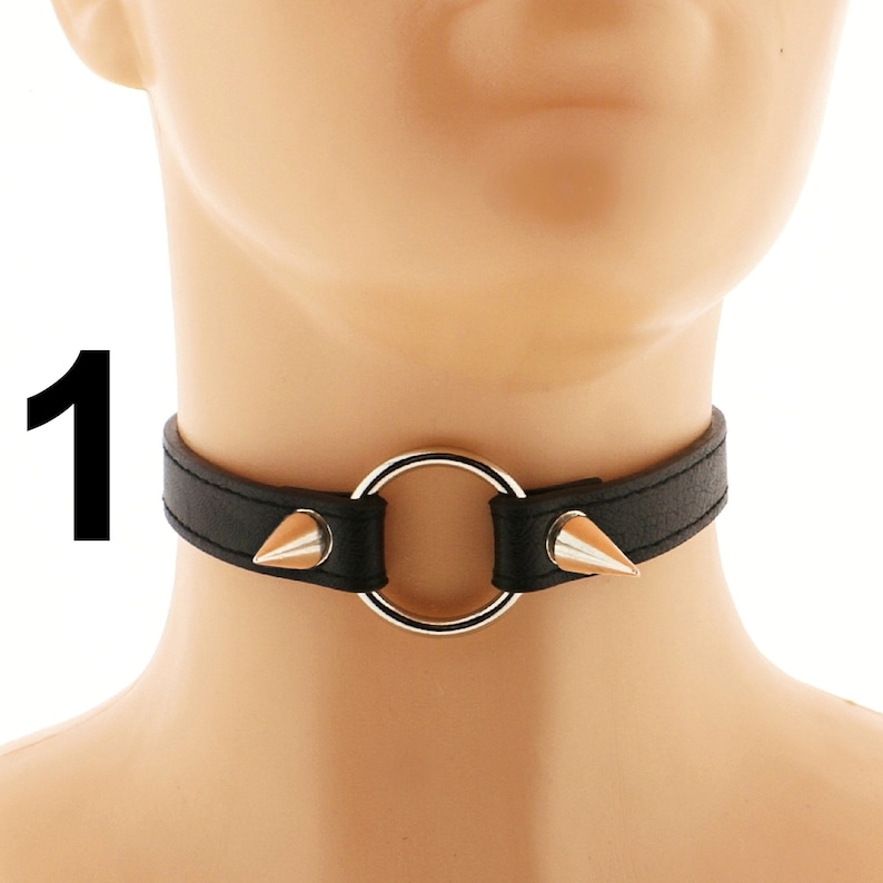 Embrace a punk or rock style with this fashionable choker made from vegan leather. Its sleek design includes a heart ring, spiked accents, and an adjustable buckle closure, all in a striking all-black color.