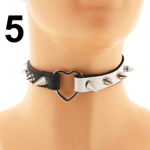 This rock punk necklace is crafted from vegan faux leather in white and black, featuring a heart ring and spiked adjustable buckle closure, giving it a choker collar style.