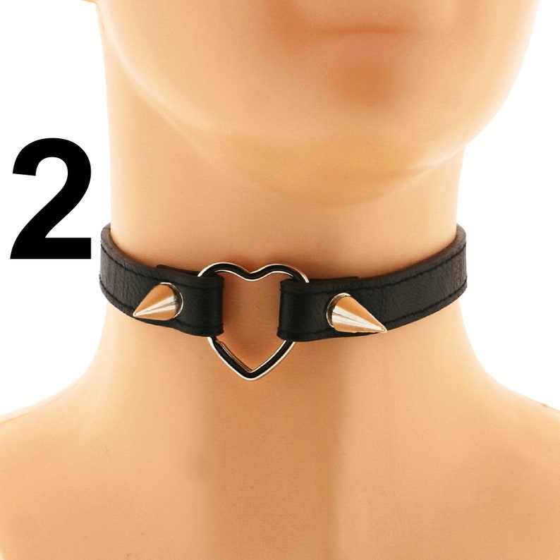 Elevate your punk or rock style with this trendy choker, meticulously crafted from vegan leather. Its edgy design features a heart ring, spiked details, and an adjustable buckle closure, all in a sleek all-black hue.