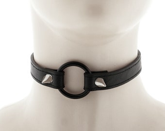colletto girocollo realizzato in ecopelle completamente nera con anello e collana con chiusura regolabile a spillo e fibbia per una vestibilità ispirata allo stile punk