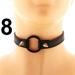 This all-black choker, crafted from vegan leather, showcases a stylish heart ring and spiked design. It features an adjustable buckle closure, making it perfect for those who embrace a punk or rock style.