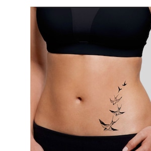 May include: A black temporary tattoo of a flock of birds flying in a diagonal line on a person's lower abdomen.
