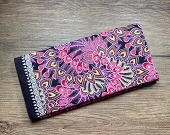 May include: A black fabric with a pink, brown, and white paisley pattern. The fabric has a white trim around the edges.