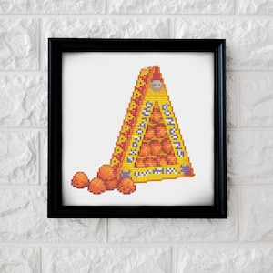 May include: A cross-stitch pattern of a yellow triangular box filled with orange spheres. The box has a purple and yellow design and the text "ORANGE" on the front. There are five orange spheres scattered on the ground in front of the box.