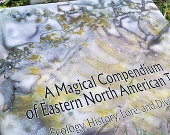 May include: A book titled "A Magical Compendium of Eastern North American Trees: Ecology, History, Lore, and Divination" by Dana Driscoll. The cover features a watercolor-style design of leaves in shades of green, brown, and purple.