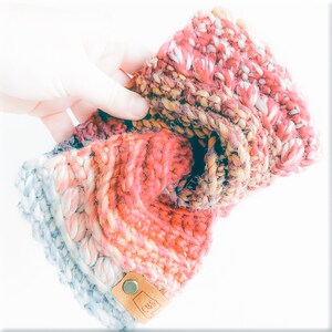 May include: A multi-colored knitted headband with a brown leather tag that says "Crag" in white lettering.