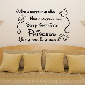 Op de afbeelding: Zwarte en witte muursticker met een grillige quote: "Met een vlinderkus en een lieveheersbeestje knuffel, slaap lekker kleine prinsesje als een beestje in een tapijt". De sticker toont een vlinder, een lieveheersbeestje en een rups.