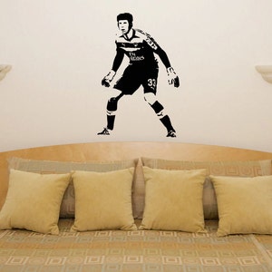Peut inclure: Autocollant mural en silhouette noire et blanche d'un joueur de football en position de gardien de but. Le joueur porte un maillot avec le texte "Fly Emirates" et le numéro "33".