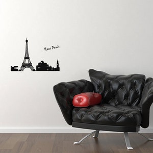 May include: Black and white silhouette of the Eiffel Tower and other Parisian landmarks with the text "I Love Paris" on a white wall. A black leather armchair with a red cushion sits in front of the wall.
