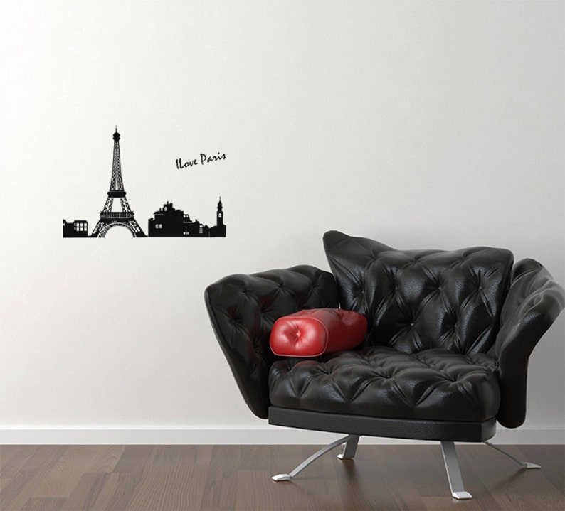 May include: Black and white silhouette of the Eiffel Tower and other Parisian landmarks with the text "I Love Paris" on a white wall. A black leather armchair with a red cushion sits in front of the wall.
