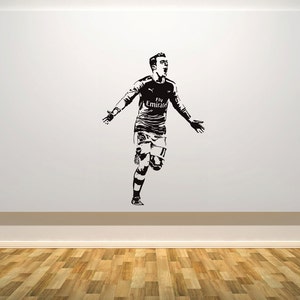 May include: Black and white silhouette of a soccer player celebrating a goal. The player is wearing a jersey with the text "Fly Emirates" on the front.