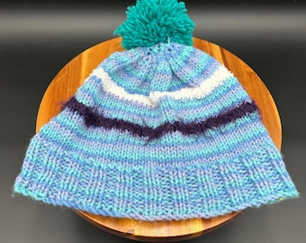 Gorro de punto hecho a mano con pompón y rayas azules y moradas para invierno