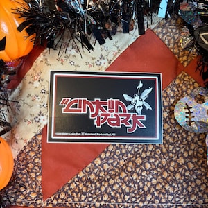 May include: A rectangular sticker featuring the Linkin Park logo in white and red text against a black background. The design includes a stylized winged figure and the text 12200 ©2001 Linkin Park Winterland Produced by LPGI at the bottom edge.