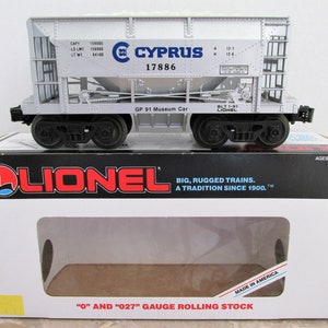 May include: A silver Lionel model train car with the words "CYPRUS 17886" printed on the side. The car is a GP 91 Museum Car and is made in America. The box is white with the Lionel logo and the words "BIG, RUGGED TRAINS. A TRADITION SINCE 1900." printed on it.