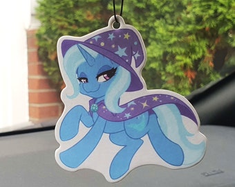 Op de afbeelding: Een blauwe en paarse cartoonpony met een paarse en witte sterrenhoed en een paarse cape met witte sterren. De pony heeft een lichtblauwe manen en staart.