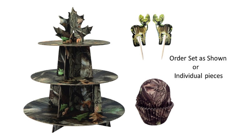 May include: Three-tiered cardboard cake stand with a camouflage pattern. The top tier has a green leaf design. Two deer cupcake toppers and a camouflage cupcake liner are also included. Order Set as Shown or Individual pieces.
