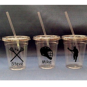 May include: Five clear plastic cups with straws and personalized lacrosse designs. The cups have the names "Steve", "Mike", and "Tom" printed on them, along with lacrosse stick and ball imagery.