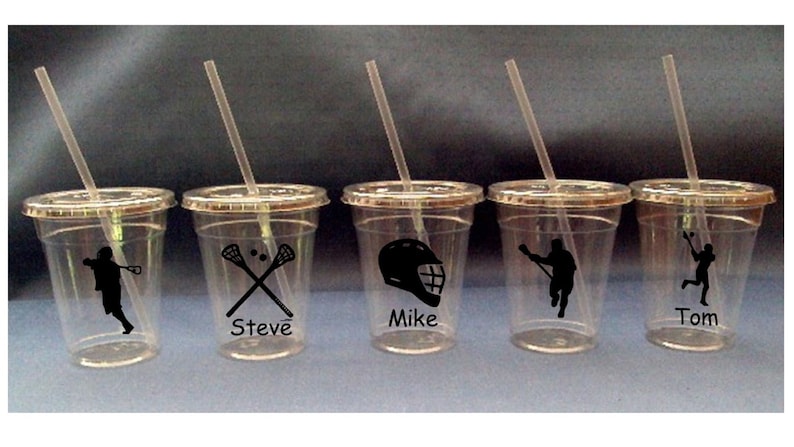 May include: Five clear plastic cups with straws and personalized lacrosse designs. The cups have the names "Steve", "Mike", and "Tom" printed on them, along with lacrosse stick and ball imagery.
