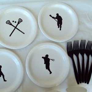 May include: White paper plates with black lacrosse-themed graphics. The plates feature crossed lacrosse sticks, and silhouettes of lacrosse players in action. Six black plastic forks are also included, perfect for a sports-themed party or event.