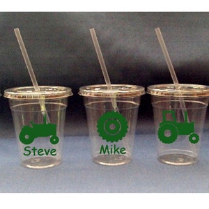May include: Five clear plastic cups with green tractor designs and names "Steve", "Mike", and "Tom" printed on them. Each cup has a straw.
