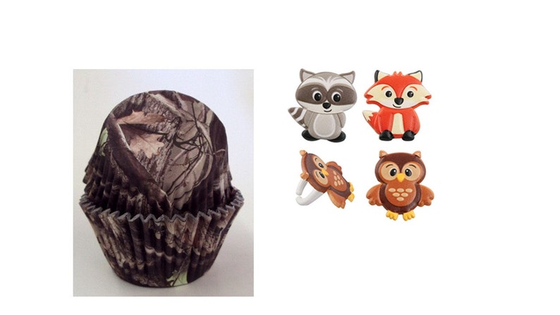 May include: A stack of camouflage-patterned cupcake liners and four woodland-themed embellishments. The embellishments include a raccoon, fox, and two owls. The cupcake liners have a brown, green, and tan pattern.