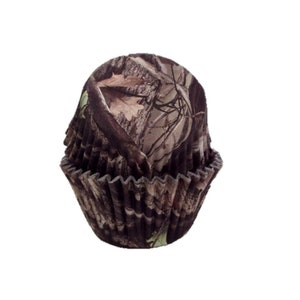 May include: Camouflage patterned cupcake liners. The liners are brown, tan, and green with a woodland pattern.