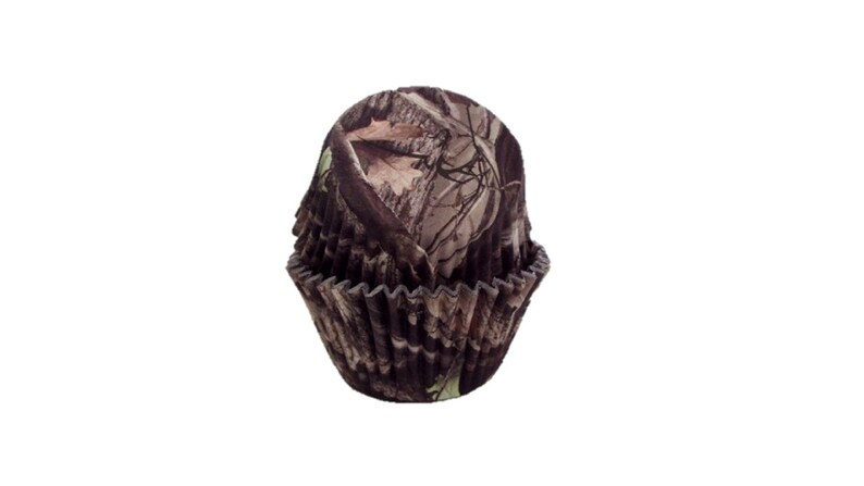 May include: Camouflage patterned cupcake liners. The liners are brown, tan, and green with a woodland pattern.