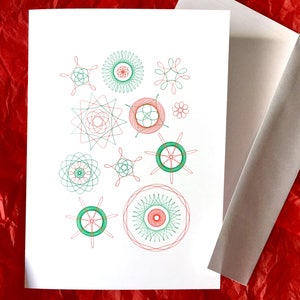 May include: A white card featuring a collection of green and red geometric designs, created using a spirograph. The designs are all different shapes and sizes, and are arranged in a random pattern.