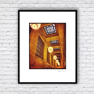 May include: A photograph of a grand, ornate interior with a high ceiling and multiple chandeliers hanging from the ceiling. The chandeliers are made of clear glass and have a warm, golden glow. The walls are a warm, golden color and the ceiling is a light, cream color. The photograph is taken from a low angle, looking up at the chandeliers.