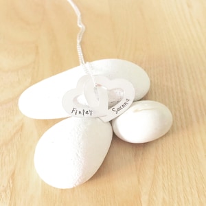 May include: Silver necklace with two interlocking heart pendants. The hearts are engraved with the names "Finlay" and "Seannah".