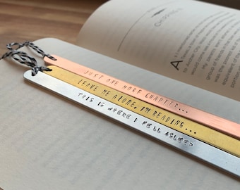 May include: Three metal bookmarks with different sayings. The top bookmark is copper and says "Just one more chapter..." The middle bookmark is gold and says "Leave me alone. I'm reading..." The bottom bookmark is silver and says "This is where I fell asleep."