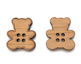 May include: Two wooden bear-shaped buttons with red stitching around the edges and three holes each.