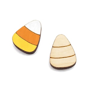 May include: Two wooden candy corn shapes, one painted with yellow, orange, and white stripes, and the other with etched lines. The candy corn is a classic Halloween treat.