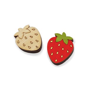 May include: Two wooden strawberry shapes, one is natural wood color and the other is painted red with yellow seeds.
