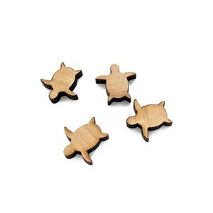 May include: Four small wooden turtle cutouts with a light brown finish. Each turtle has a distinct shape, with a body, head, and flippers. The turtles are arranged on a white background.