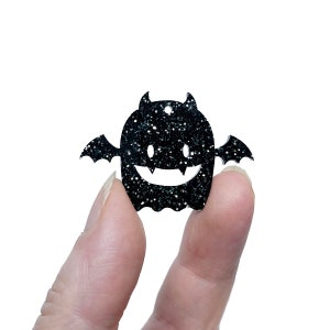 May include: Black glitter ghost with bat wings and a smiling face.