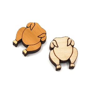 May include: Two wooden ornaments shaped like roasted chickens. One is brown and the other is natural wood.