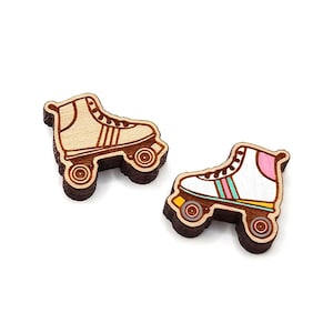 May include: Two wooden roller skate charms, one with a beige boot and the other with a white boot with pink and green stripes.