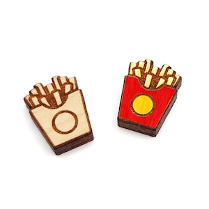 May include: Two wooden earrings shaped like french fries in a box. One earring is painted red with a yellow circle, the other is natural wood.