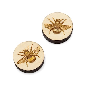 May include: A pair of wooden earrings with a laser-engraved image of a bee on each earring.