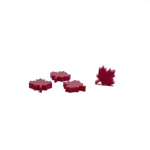 May include: Four red maple leaf shaped game pieces. Three are lying flat and one is standing upright.