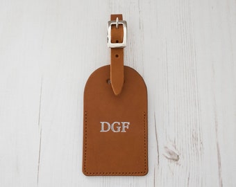 May include: A brown leather luggage tag with a silver buckle and the initials "DGF" embossed in white.