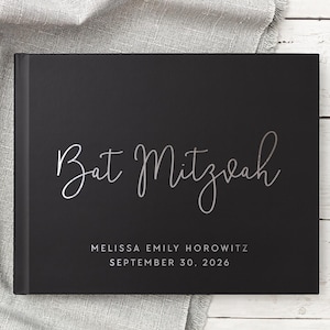 May include: Black guest book with silver lettering that reads "Bat Mitzvah" and "Melissa Emily Horowitz September 30, 2026".