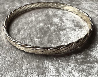 Op de afbeelding: Een zilveren armband met een gedraaid ontwerp.