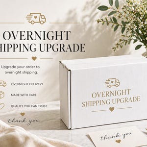May include: A white cardboard box with the text "OVERNIGHT SHIPPING UPGRADE" and a small card that says "thank you". The image also includes a vase of flowers and a pen.