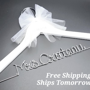 May include: White wooden hanger with a tulle bow and the words "Mrs. Crteall" in silver wire lettering.