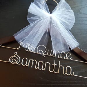 Pu&ograve; includere: Un appendiabiti in legno marrone scuro con le parole "Mrs Quince Samantha" in filo d'argento. Un fiocco di tulle bianco &egrave; attaccato in cima. Per un'occasione speciale.