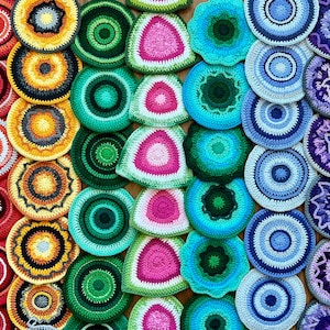 May include: A collection of colorful crocheted circles with various patterns and designs. The circles are arranged in a rainbow pattern, with red, orange, yellow, green, blue, indigo, and violet circles.