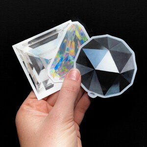 May include: Three sticker designs featuring different geometric shapes. The stickers are white with black and gray shading. The stickers are drawn to look like gemstones.