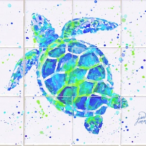 May include: A watercolor painting of a sea turtle on a white background with blue and green paint splatters. The turtle is painted in shades of blue and green, with a white shell. The artist's signature, "Jan Macapin", is in the bottom right corner.